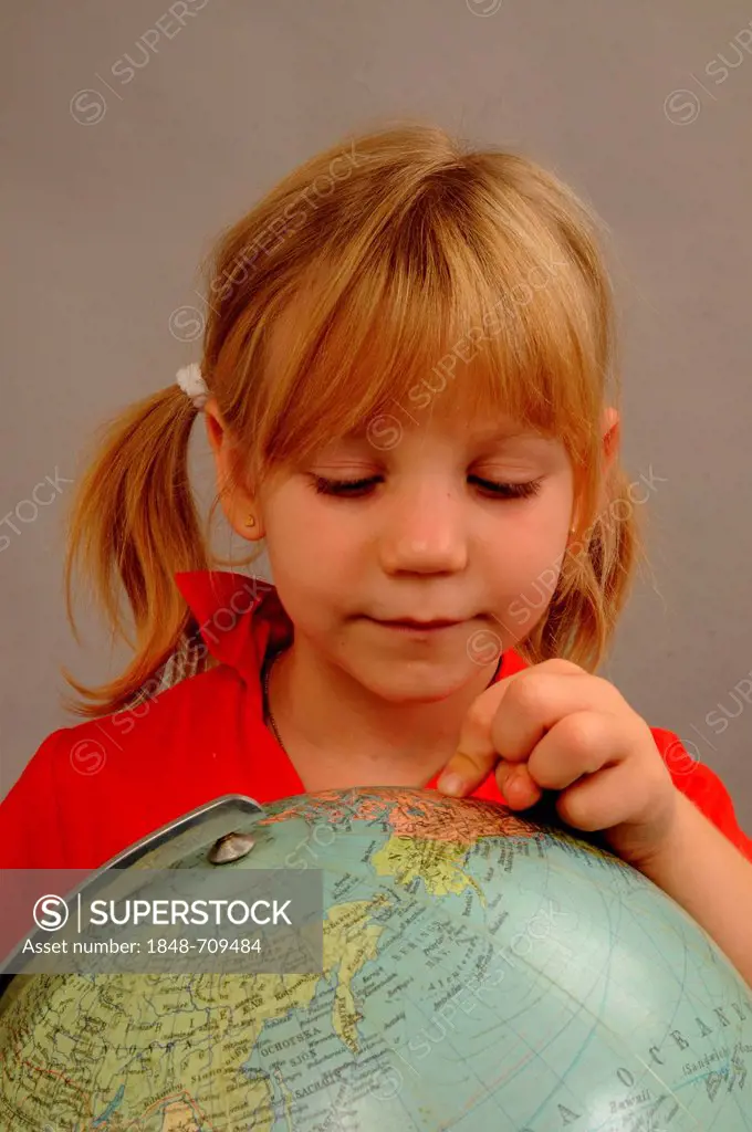 Little blonde girl, 5 years, looking at a globe