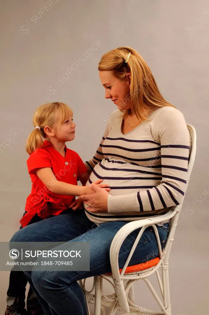 Pregnant mother sitting with her 5 years old daughter