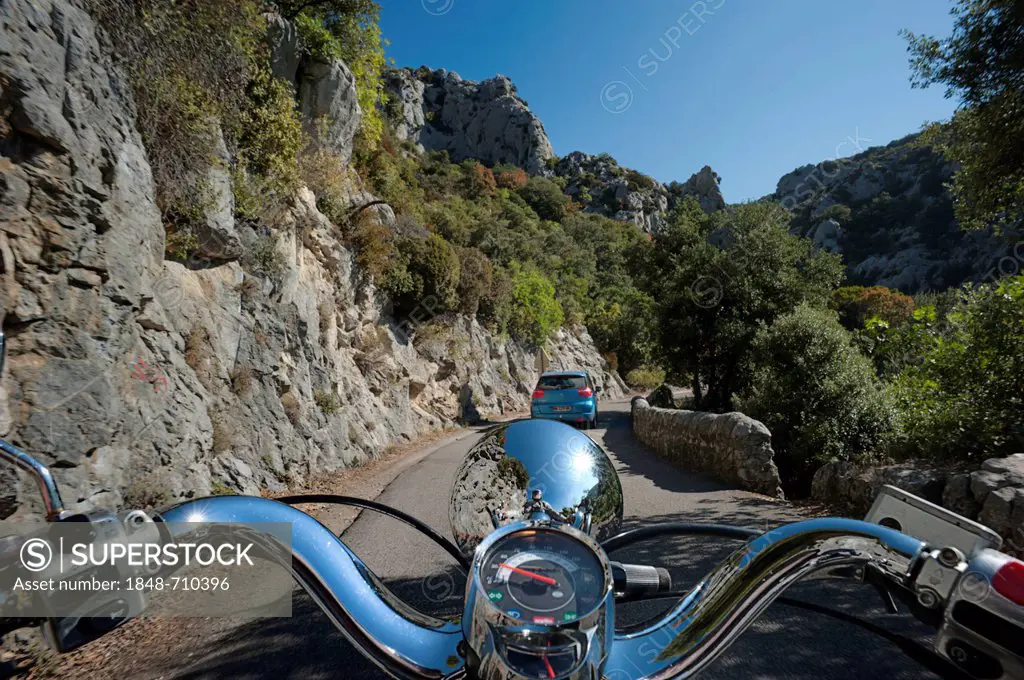 Motor scooter being driven in the Gorges de Galamus, a narrow passage between the departments Aude and Pyrénées-Orientales, Northern Catalonia, France...