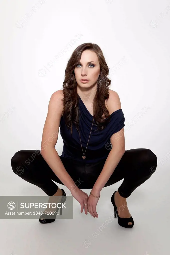 Young woman posing in a blue top, black leggings and high heels