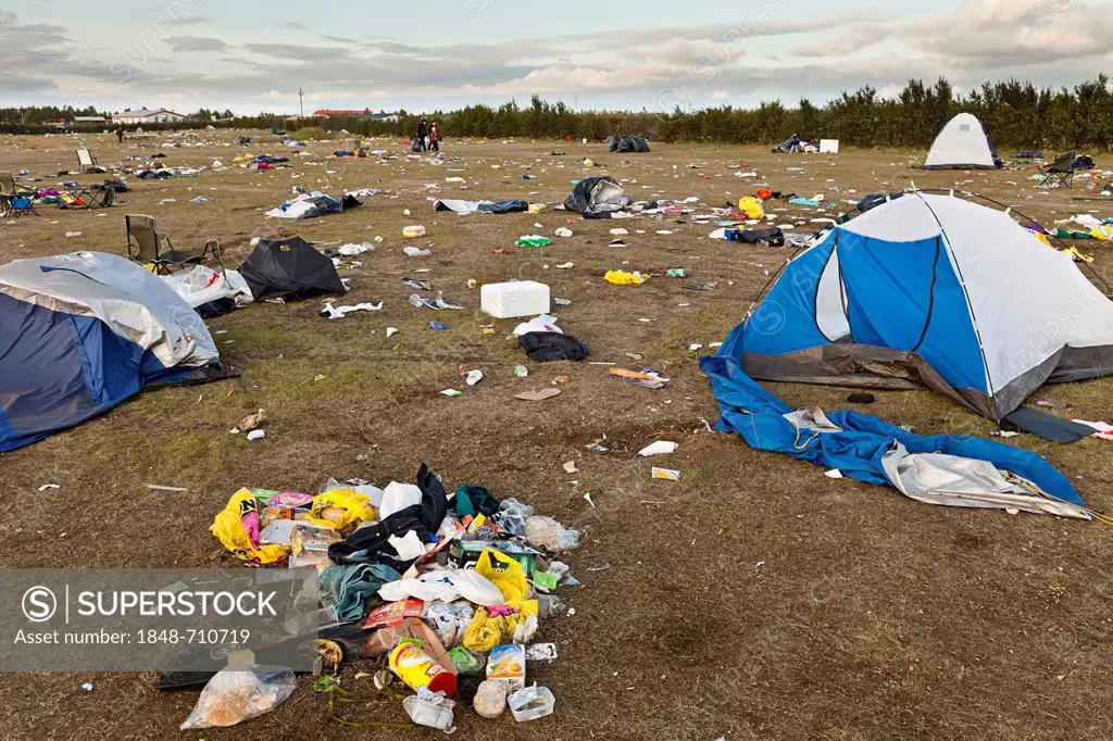 Meadow full of garbage, waste, destroyed tents and broken camping equipment after a rock concert for young people on the outskirts of Hella in the sou...