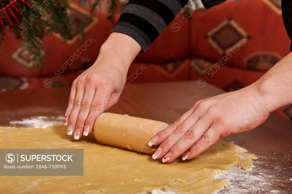 Woman's hands rolling dough with a rolling pin