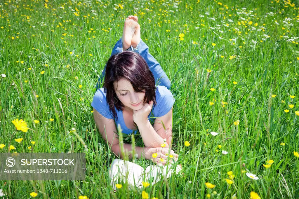 Young woman lying in the grass and reading a book