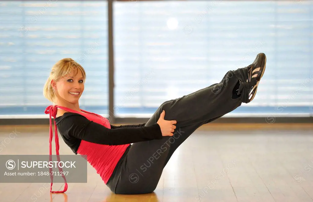 Young woman stretching, warming-up exercises, balancing exercise, yoga, Haus des Sports, House of Sport, SpOrt, Stuttgart, Baden-Wuerttemberg, Germany...