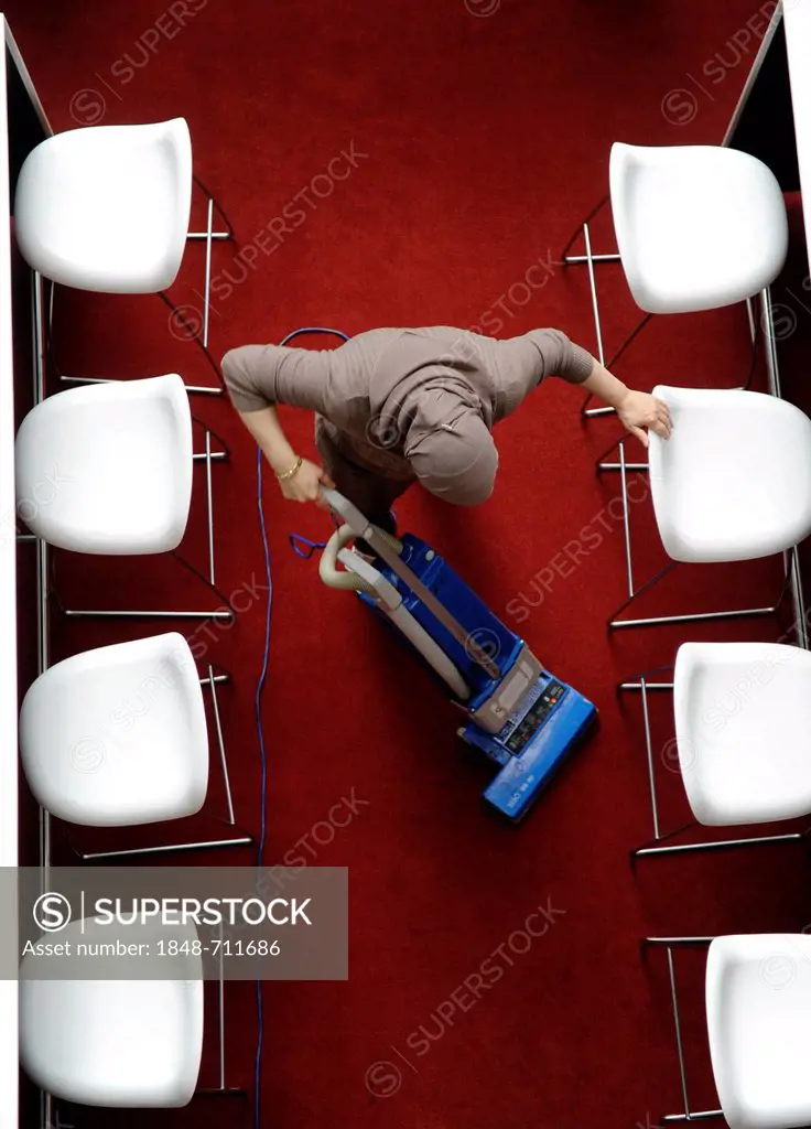 Muslim cleaning lady vacuum-cleaning the canteen of a company