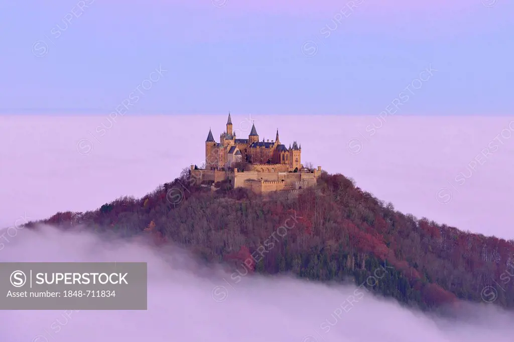 Burg Hohenzollern castle, in morning light, mist, with autumn forest, Schwaebische Alb, Swabian Alb, Baden-Wuerttemberg, Germany, Europe