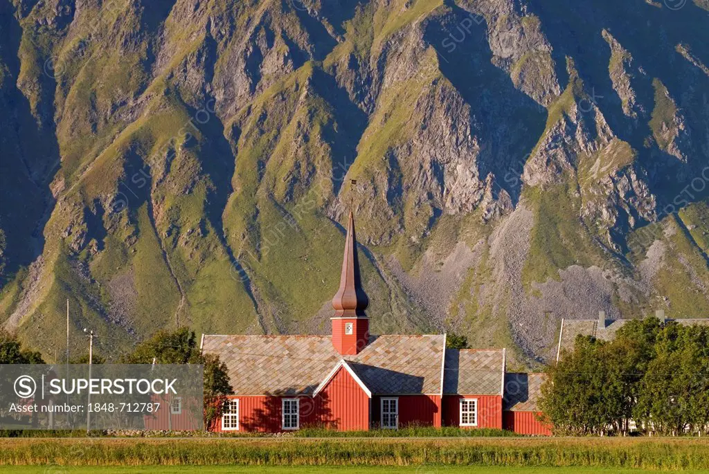 The red stave church of Flakstad in front of steep mountains, Vareid, Fredvang, island of Flakstadøya, Flakstadoya, Lofoten archipelago, Nordland, Nor...