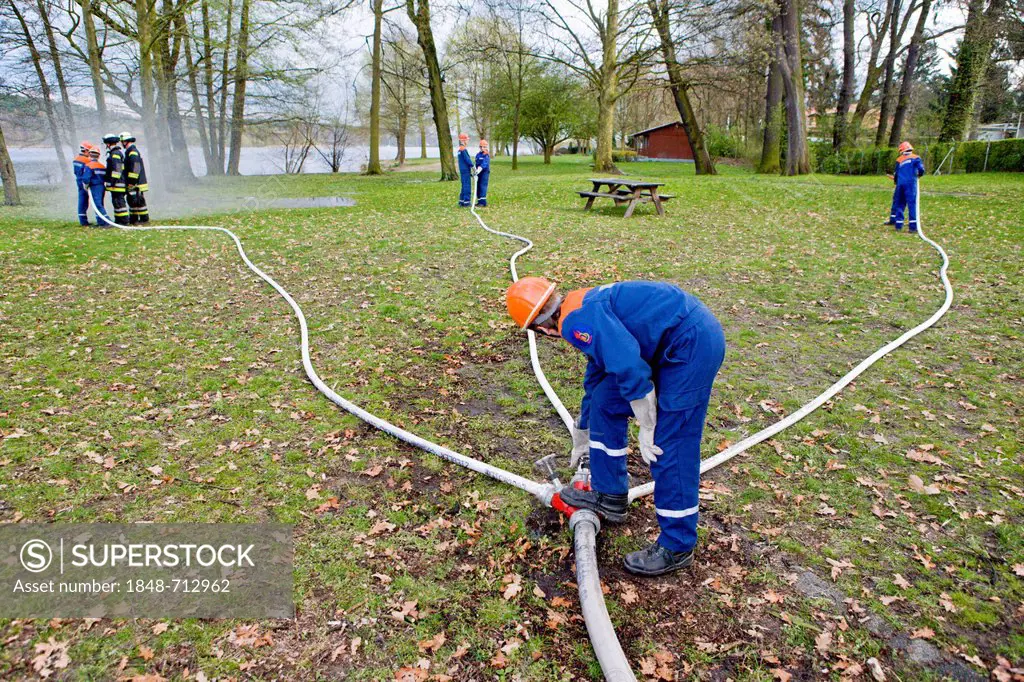 Volunteer fire brigade of Gatow, young firefighters during a firedrill on the banks of the Havel River, setup of a suction pipe, Berlin, Germany, Euro...
