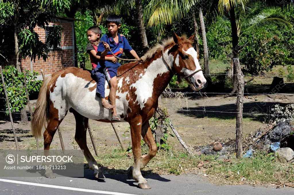 Two boys riding on horseback, El Angel, Bajo Lempa, El Salvador, Central America, Latin America