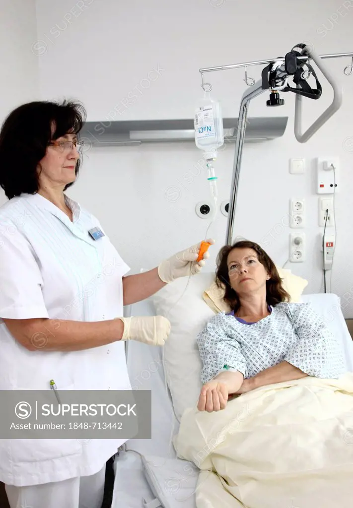 Nurse putting a patient in a hospital bed on a drip infusion, hospital