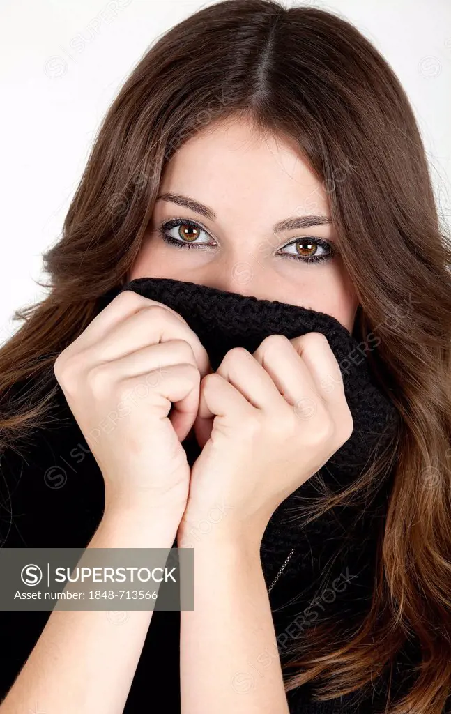 Young woman pulling up the collar of her black jumper