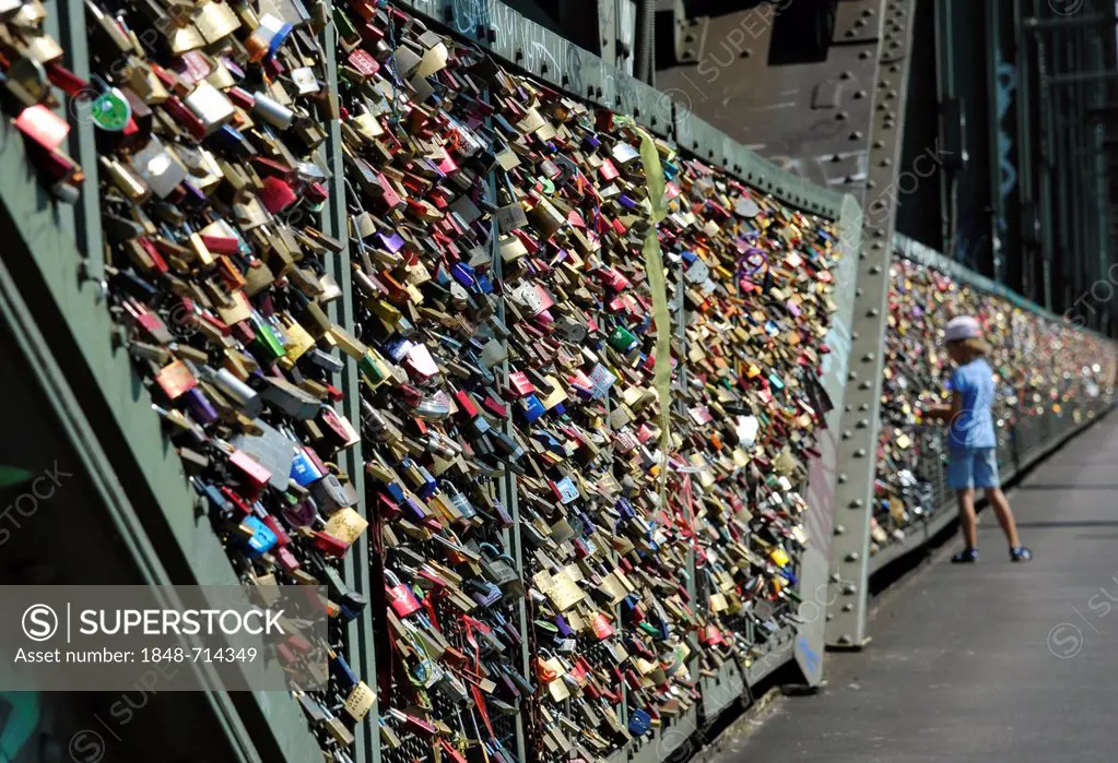 Love padlocks on security grid that separates the footpath from the railway tracks on Hohenzollern Bridge, Cologne, North Rhine-Westphalia, Germany, E...