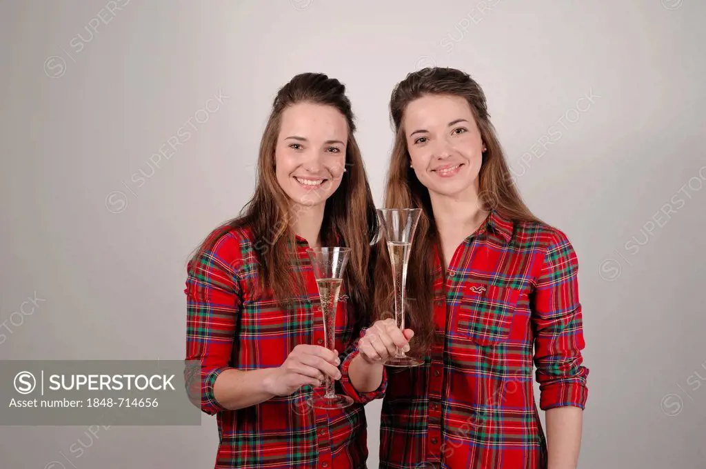 Twin sisters holding champagne glasses for a toast