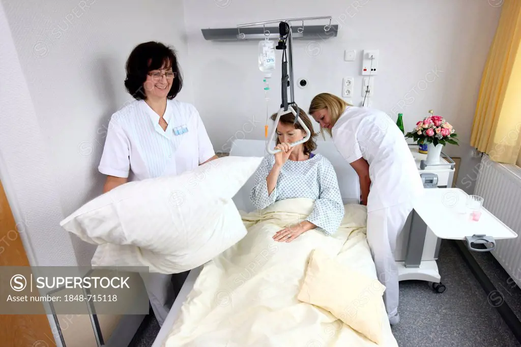 Patient lying in a hospital bed, nurses making the bed, single room, hospital
