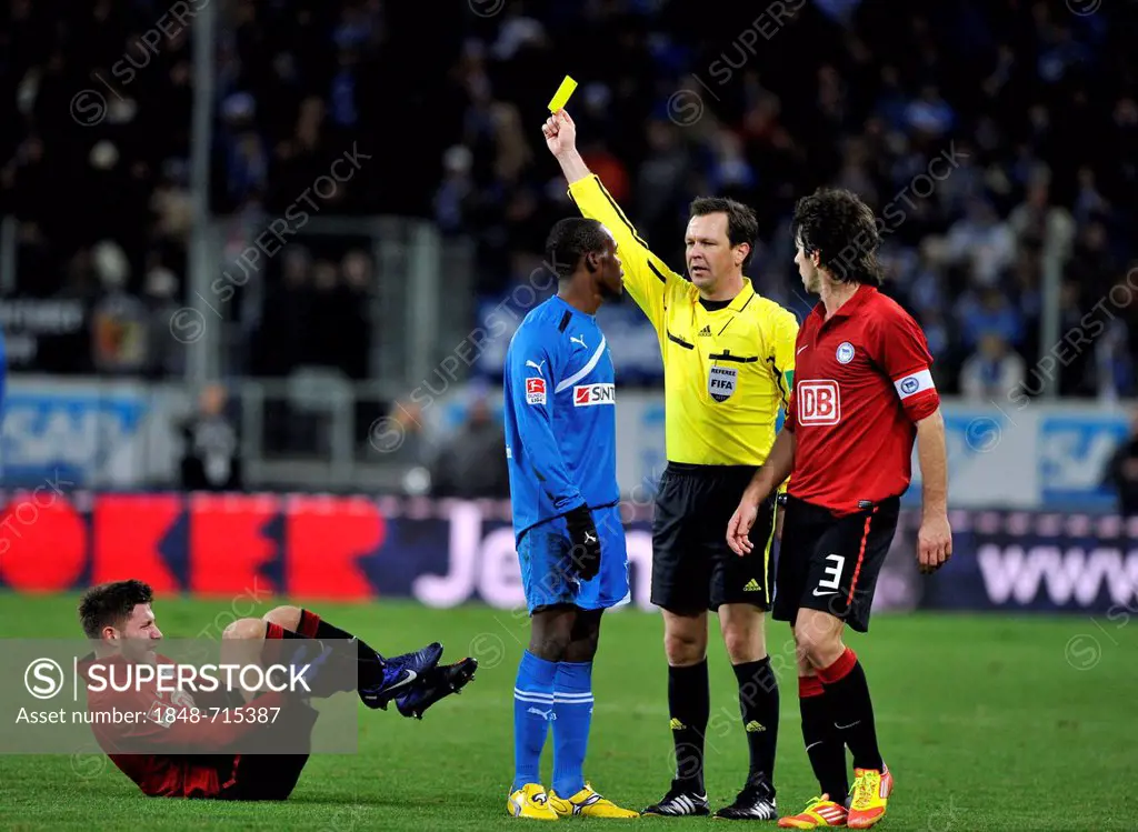 Peter Sippel, referee, showing Knowledge Musona of TSG 1899 Hoffenheim, blue jersey, the yellow card for a foul of Tunay Torun of Hertha BSC Berlin, o...