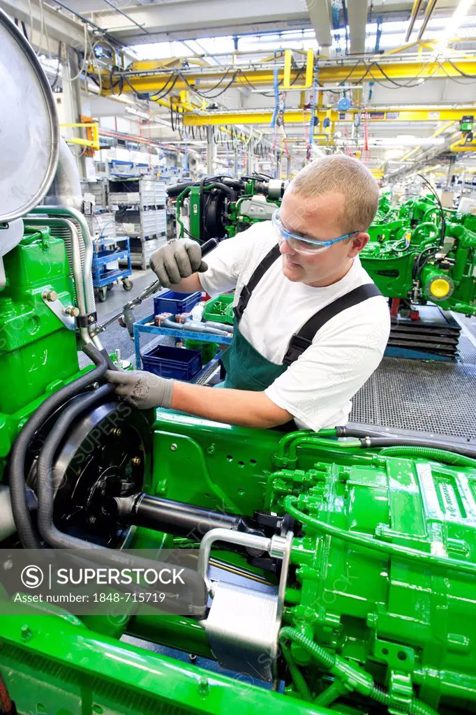 Worker is connecting hoses between the engine and the gearbox in the engine assembly area of the tractor production section at the European headquarte...