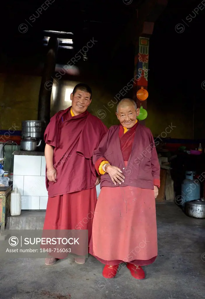 Two Buddhist nuns, one middle-aged woman, one elderly woman, over 70 years, wearing red robes at the monastery entrance, Gongkar Chode monastery, Lhas...