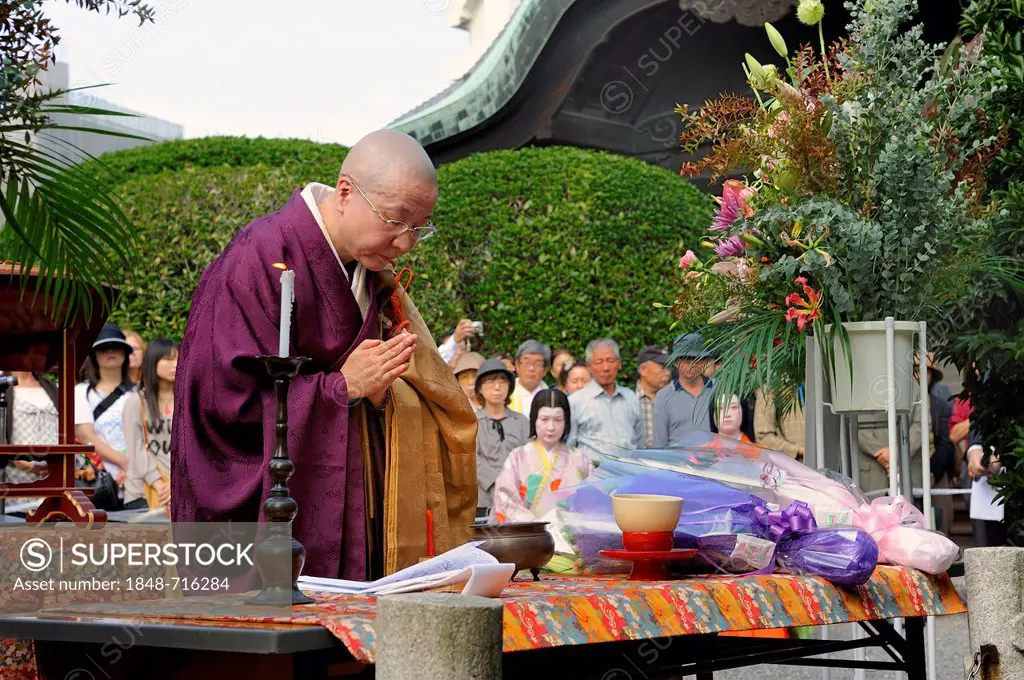 Nun praying at the alter over a pile of dolls for a Buddhist memorial service, so that the souls of the dolls can be redeemed, Hokyo-ji Temple, Kyoto,...