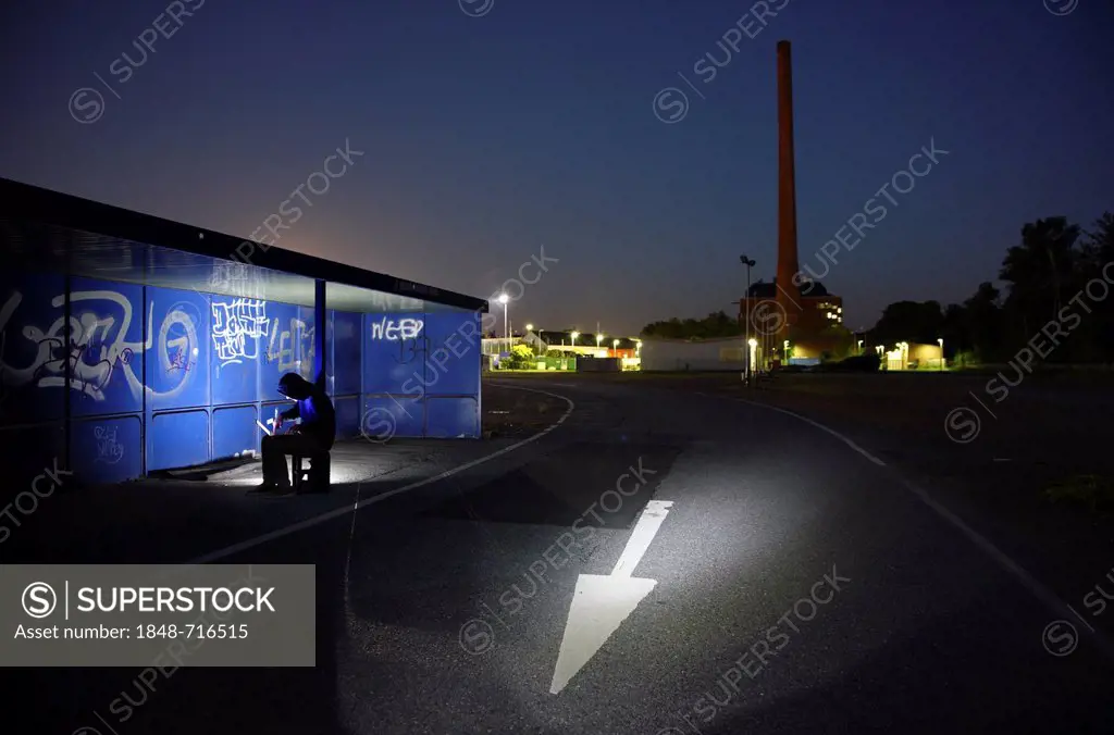 Man surfing on a laptop computer at a bus stop at night, symbolic image for computer hacking, computer crime, cybercrime, data theft
