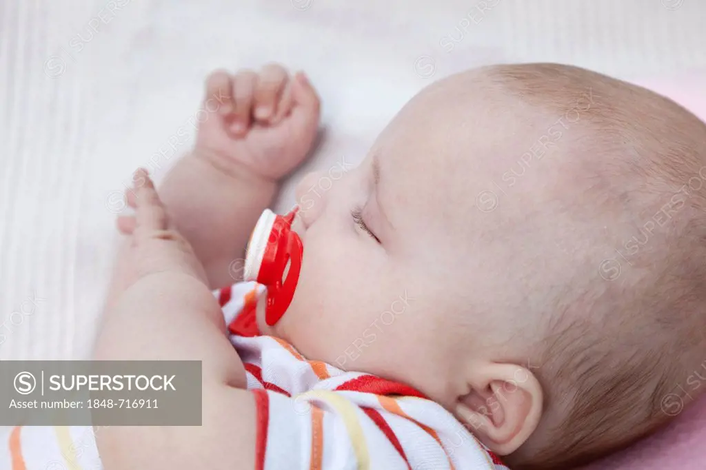 Three-month-old baby sleeping with a pacifier in its mouth