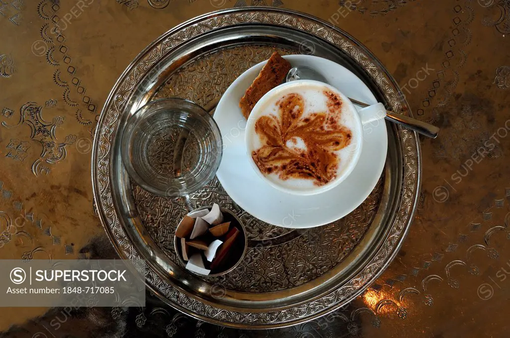 Cup of Cappuccino, glass of water and sugar sachets served on a round silver tablet with engravings, Vienna, Austria, Europe