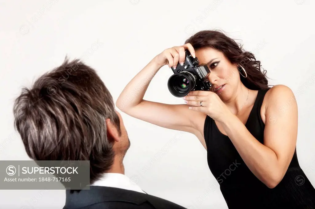 Young woman photographing a man with an old analog Nikon camera