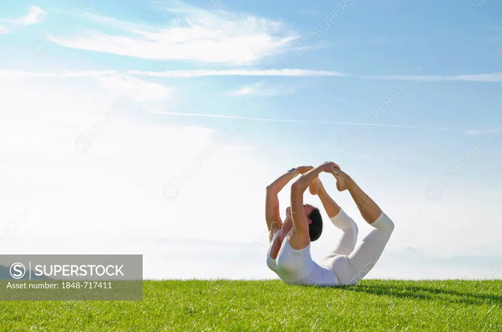 Young woman practising Hatha yoga outdoors, showing the pose dhanurasana, bow pose, Nove Mesto, Okres Teplice, Czech Republic, Europe