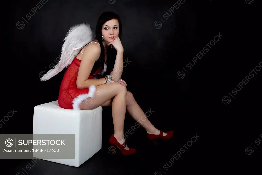 Young woman posing in red Christmas lingerie with angel wings