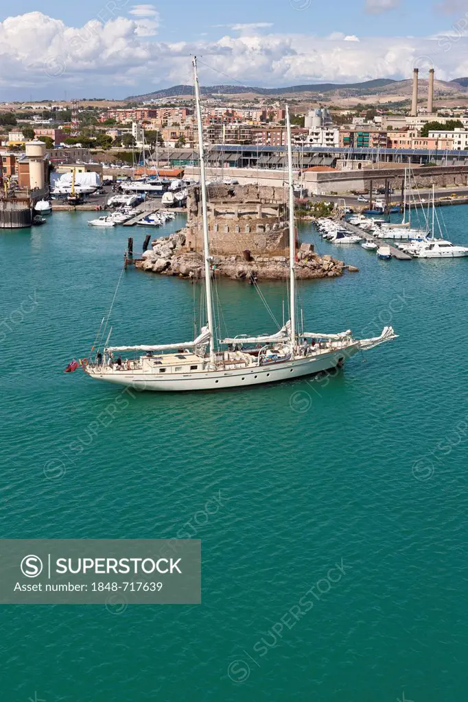 Sailing yacht passing the historical backdrop in the port of Civitavecchia, Rome, Italy, Europe