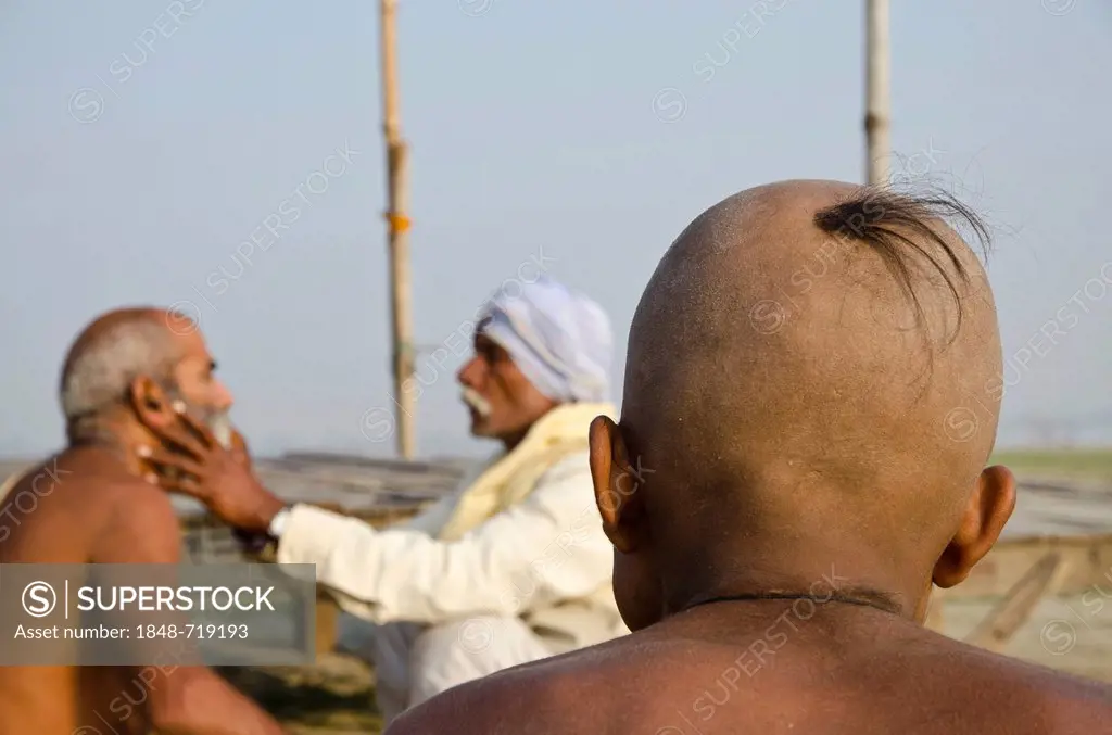 Shaving the head as part of a religious ritual, performed at Sangam, the confluence of the holy rivers Ganges, Yamuna and Saraswati, in Allahabad, Utt...