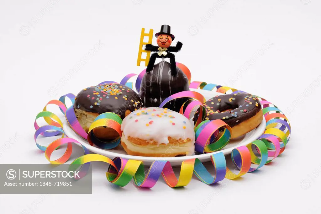 Doughnuts and glaced filled doughnuts on a plate with New Year's decorations, a garland and a chimney sweep