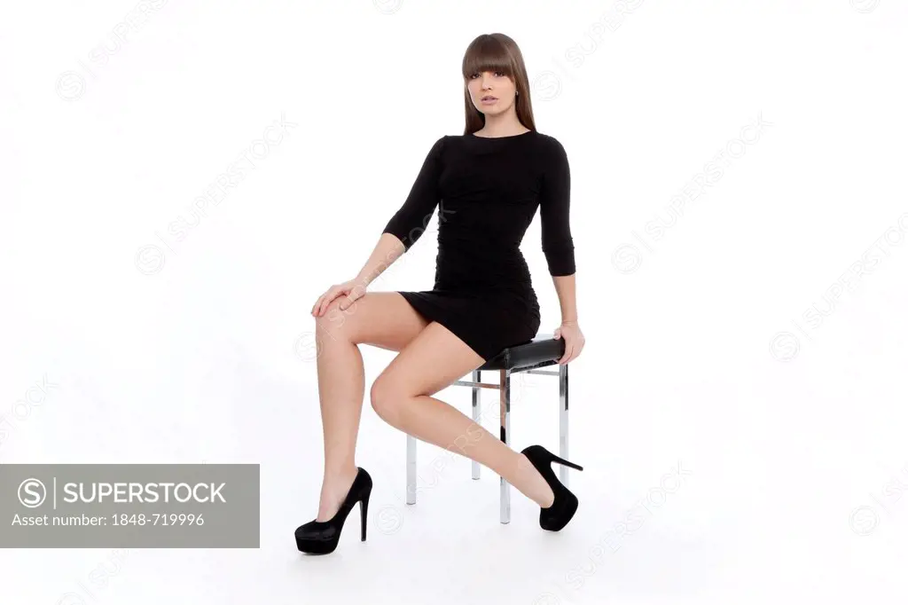 Young woman posing confidently in a short black dress with high heels