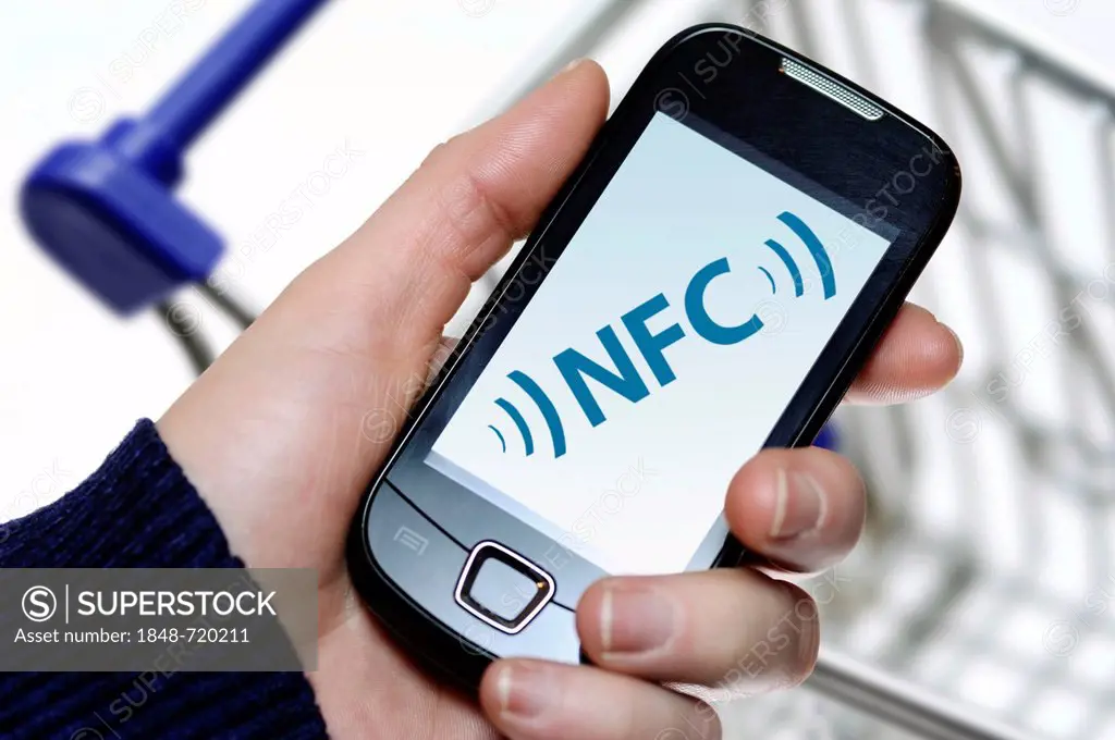 Hand holding a smartphone displaying NFC, Near Field Communication