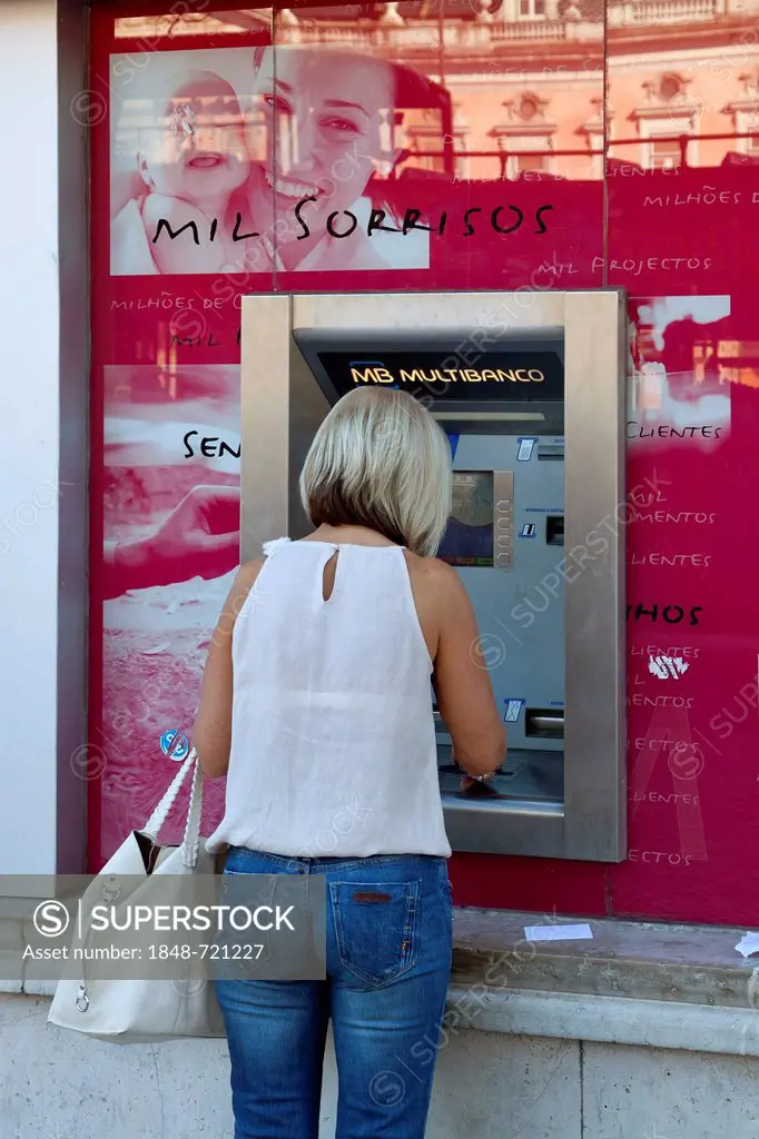 Woman at an ATM at a branch of the Portuguese bank Millennium BCP, Banco Comercial Portugues, Portuguese Commercial Bank, Lisbon, Portugal, Europe