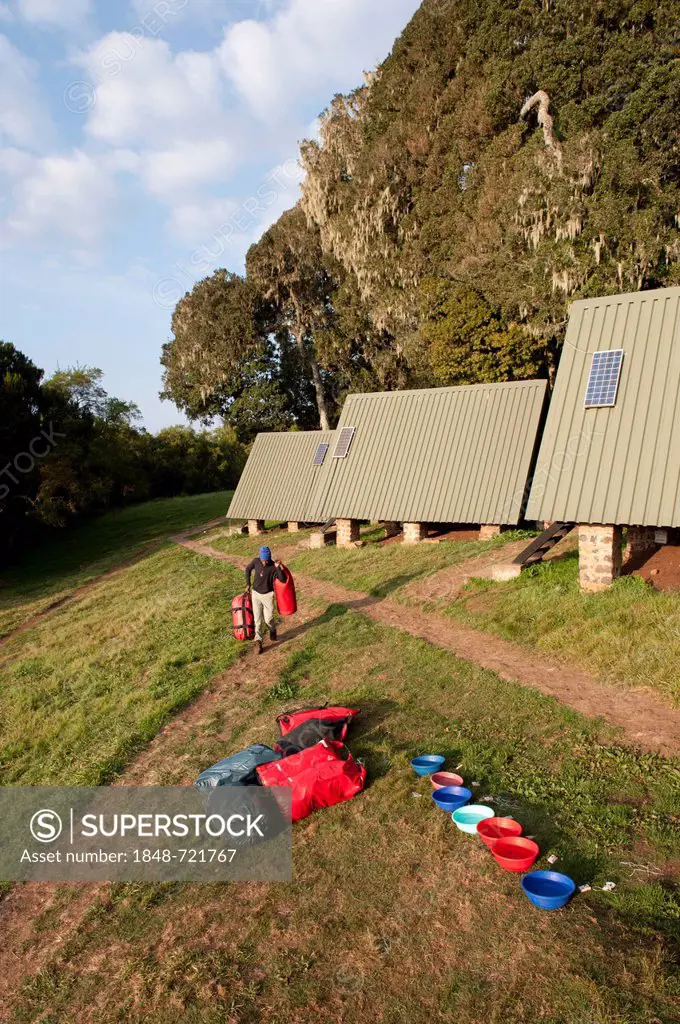 Mountaineering, trekking, carrier with luggage outside mountain huts, plastic bowls for washing, Mandara Hut, Marangu route, Mount Kilimanjaro, Kibo, ...