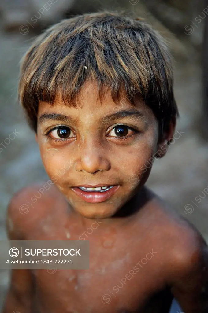 Portrait, cheeky boy with his face and body smeared with clay, the boy works with his family under the slavery-like practice of debt bondage in a bric...