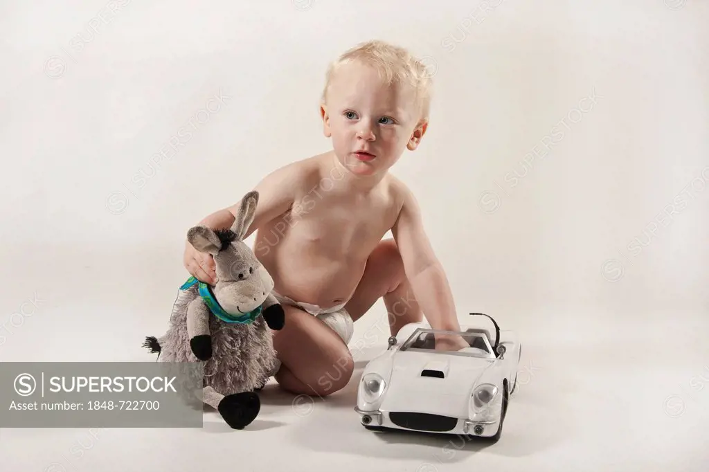 Toddler, boy, 1, playing with a toy car and a stuffed donkey