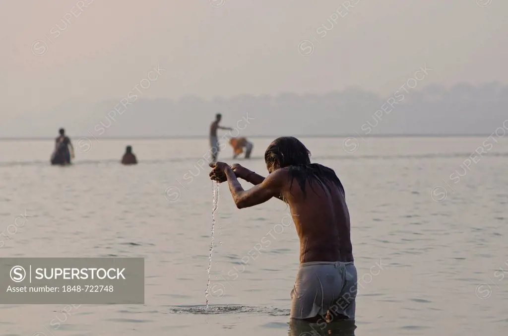 Pilgrim praying at Sangam, the confluence of the holy rivers Ganges, Yamuna and Saraswati, in Allahabad, Uttar Pradesh, India, Asia