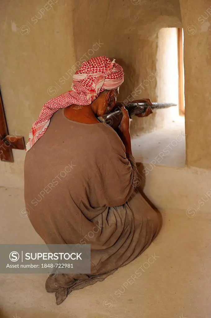 Figure dressed as an Arab warrior shooting through an embrasure, Oasis and enclave of Hatta, Heritage Village, United Arab Emirates, Arabian Peninsula...