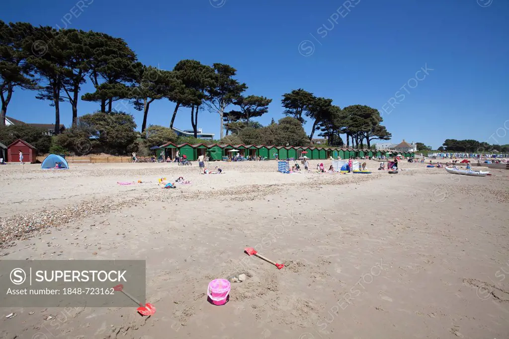 Abandoned toy bucket and spades on Mudeford beach with pine trees and beach huts, Mudeford, Dorset, England, United Kingdom, Europe