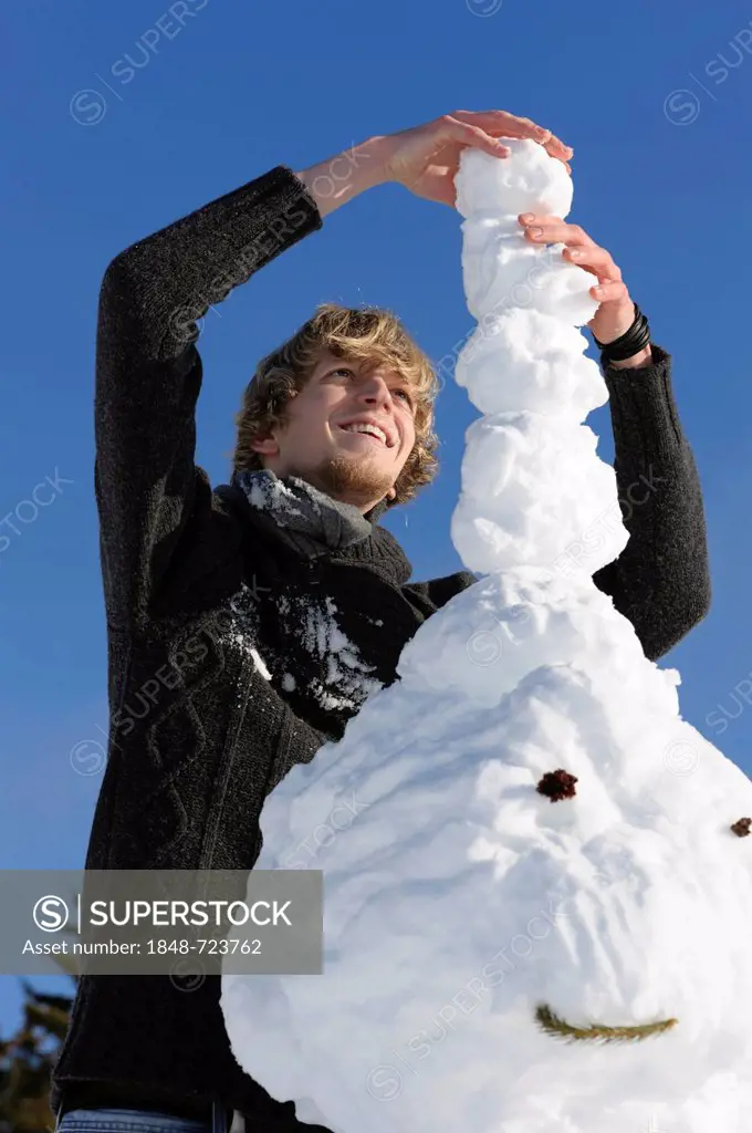 Young man building a snowman, Black Forest, Baden-Wuerttemberg, Germany, Europe, PublicGround
