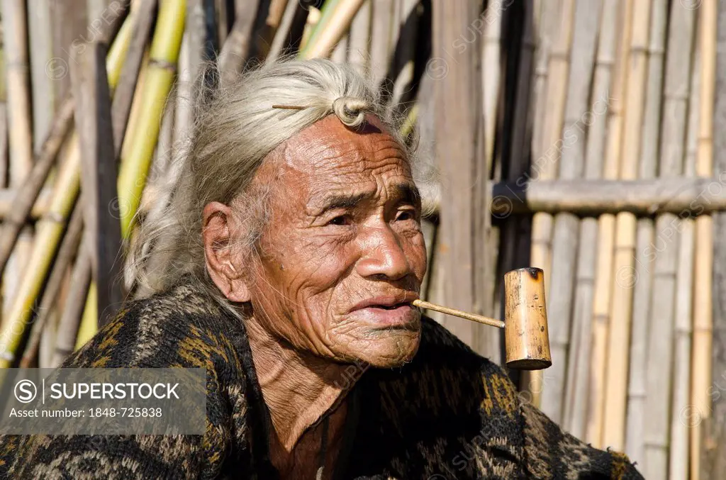 Old Apatani man with the typical hair knot at the forehead, in front of his house, Hong village, Arunachal Pradesh, India, Asia