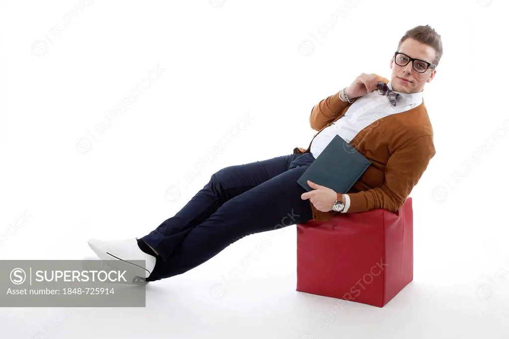 Young man with glasses and a bow tie sitting on a cube