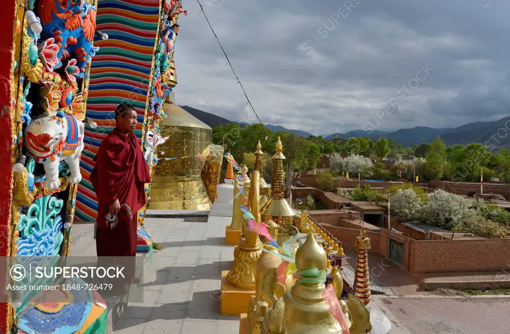 Tibetan Buddhist monk on a new painted and gilded chorten, stupa at the Wutun Si Monastery, Tongren, Repkong, Qinghai, formerly Amdo, Tibet, China, As...