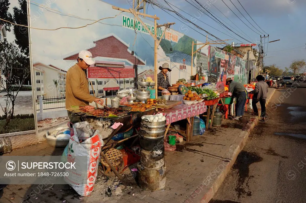 A row of food stalls in front of Vietnamese billboards, advertisement poster with projects under the name of the Vietnamese soccer club Hoàng Anh Gia ...
