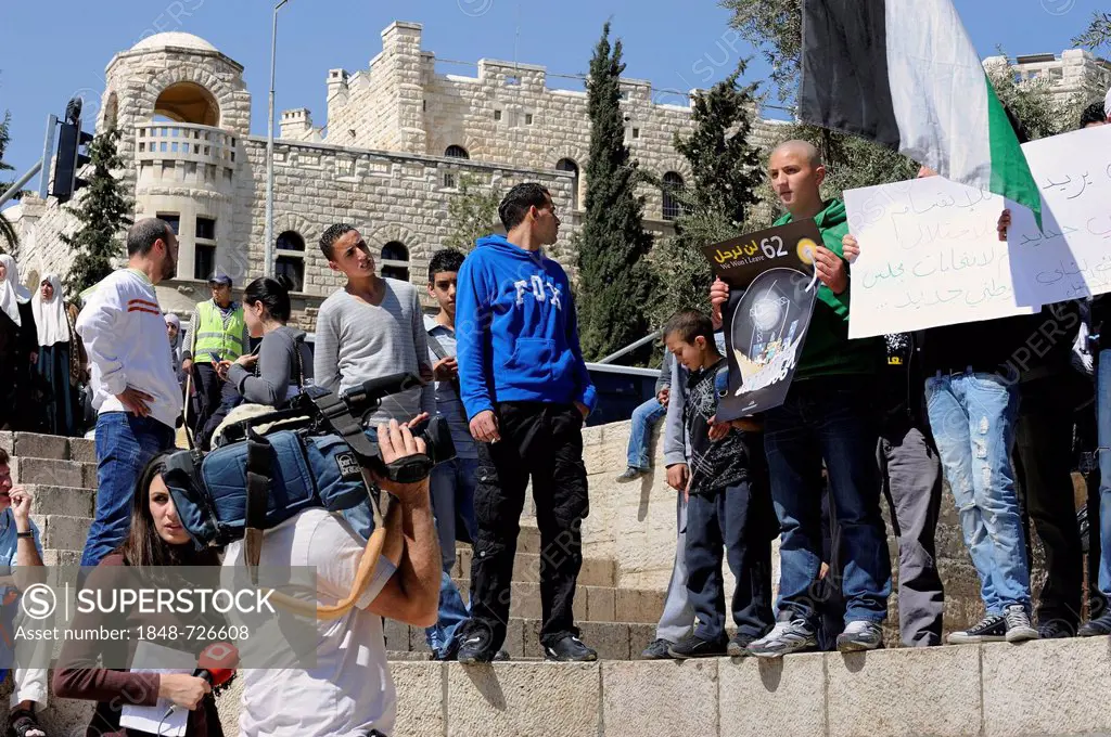 Palestinians demonstrating peacefully with placards and posters against the Israeli settlement policy in front of a camera at the Damascus Gate outsid...