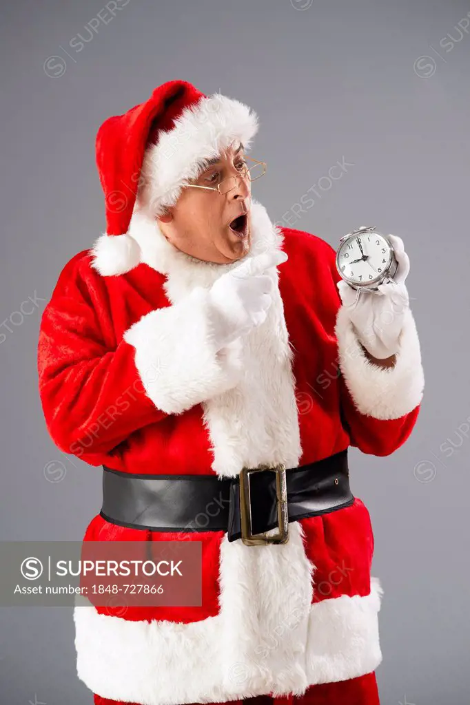 Santa Claus looking scaredly on an alarm clock