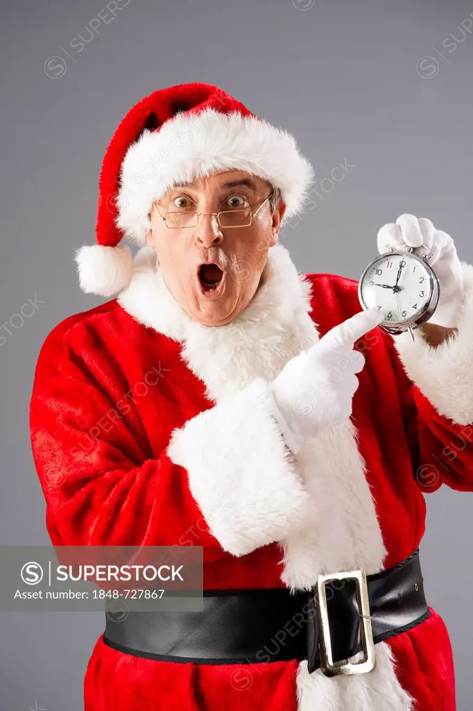 Santa Claus looking scared and pointing to an alarm clock