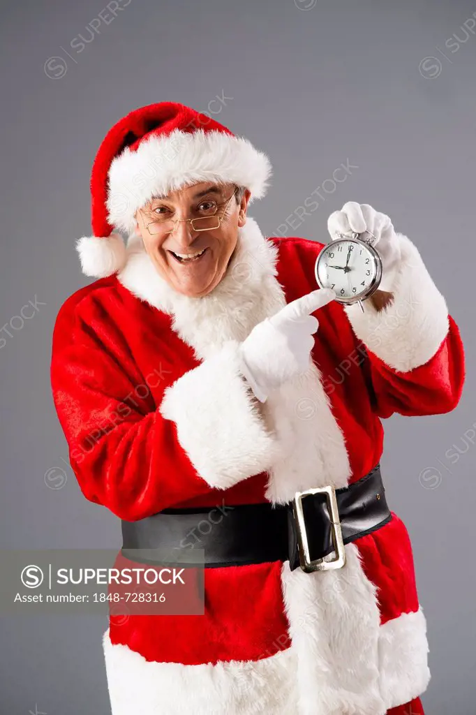 Smiling Santa Claus pointing to an alarm clock
