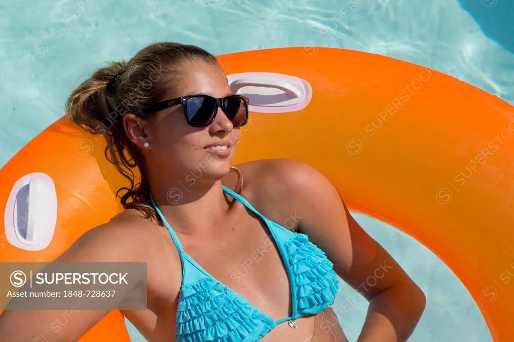 Young woman on an inner tube, floating tyre, in a private swimming pool, Germany